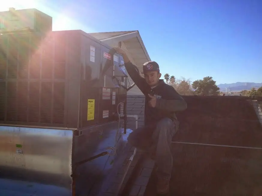 HVAC technician performing AC Tune-Up on a rooftop unit in McKenzie